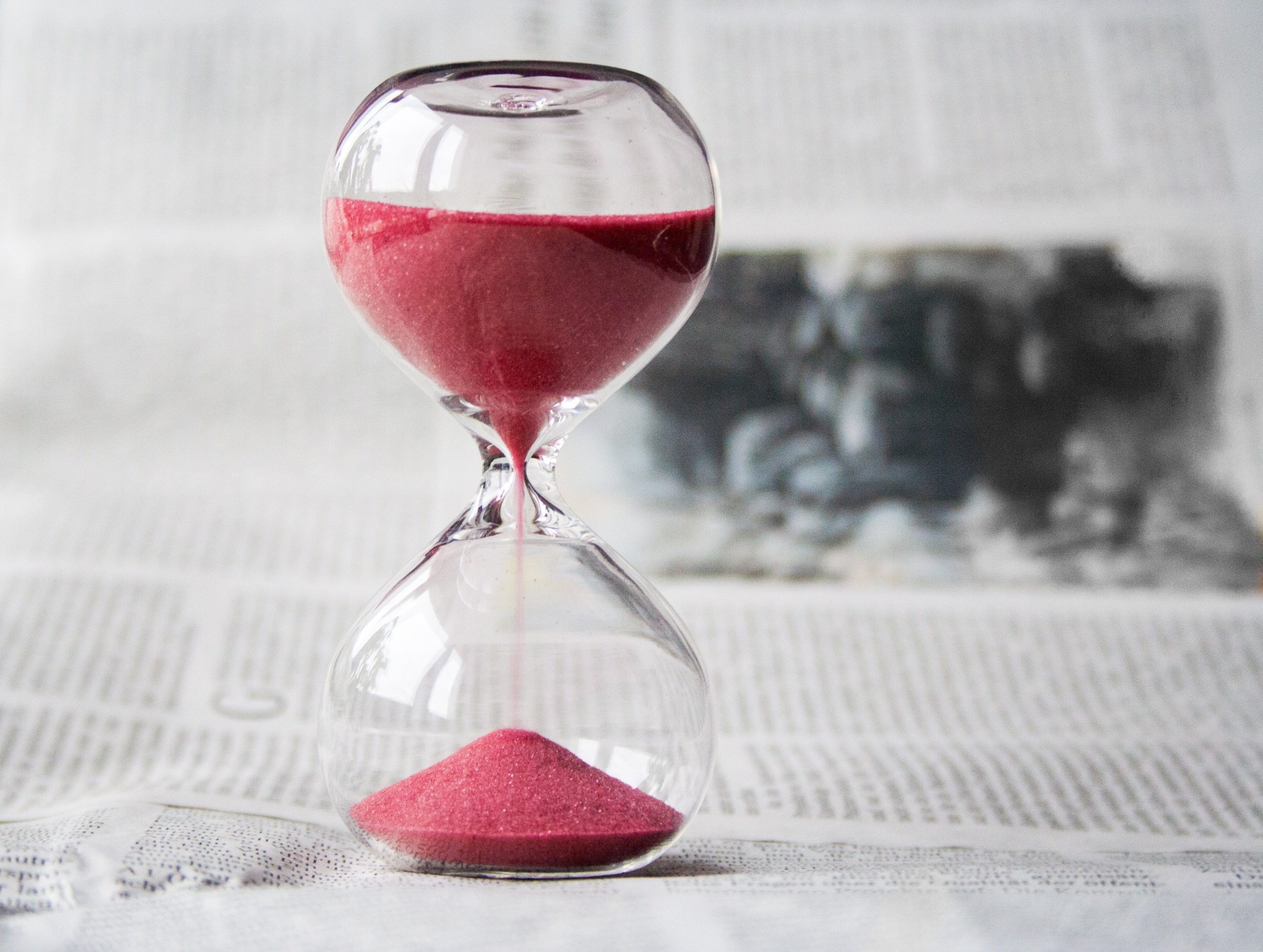 Hourglass with red sand 3/4 time left on newspaper. Want to sell your home fast, we buy fast and drama free