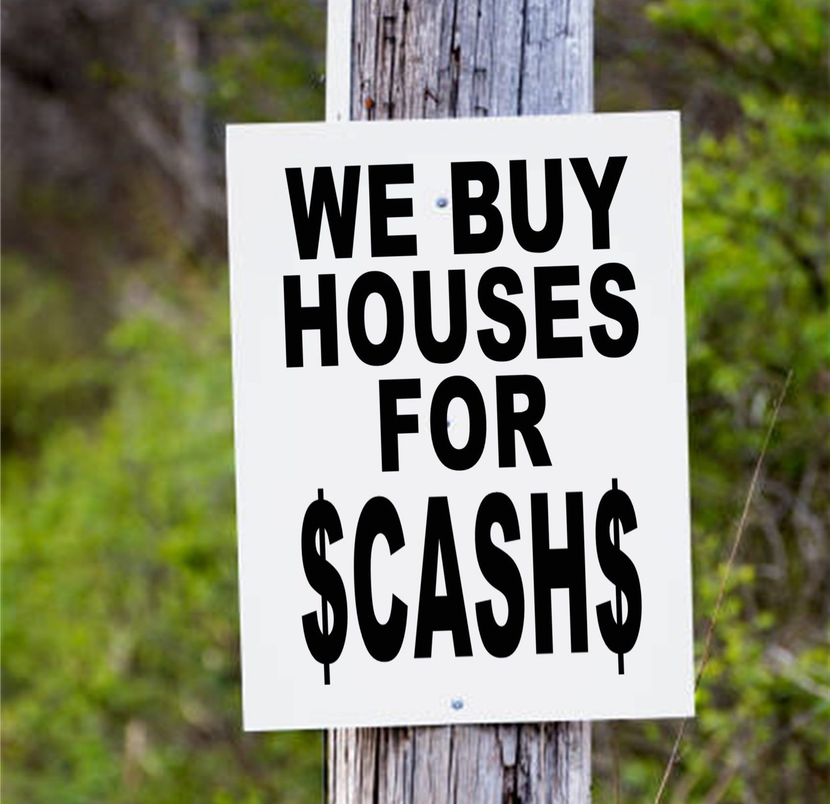 White sign on a pole saying "We Buy Houses For $CASH$"