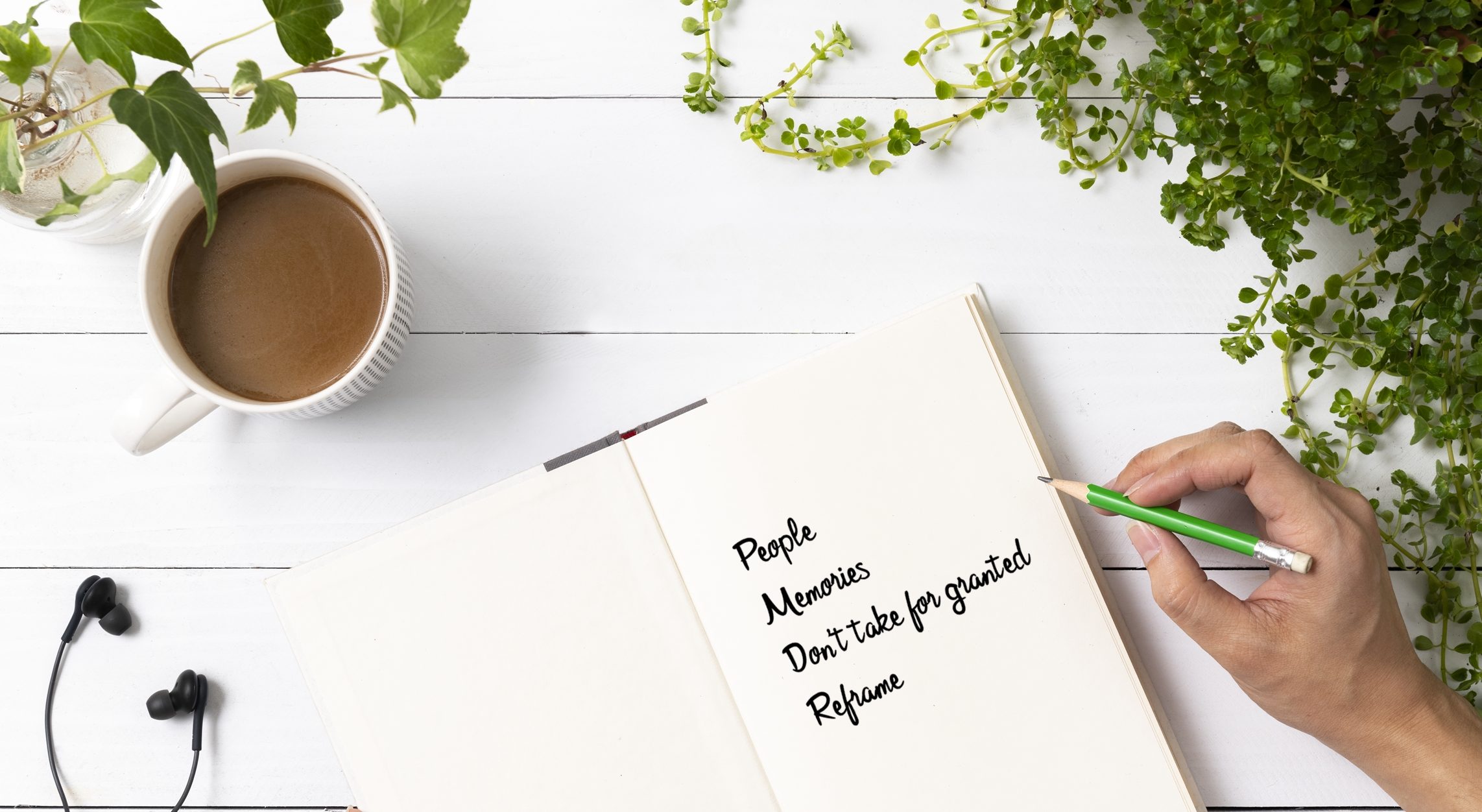 Journal on table with cup of coffee open to page with list of things to be grateful for in hard times. woman's had holding pencil